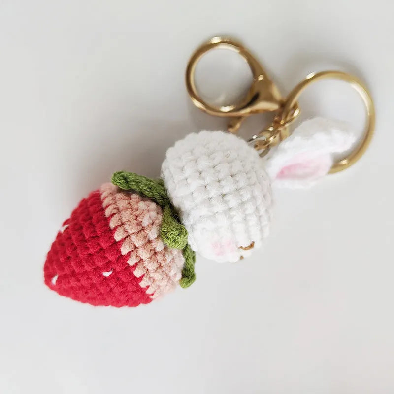 White hand-woven wire pendant in shape of a rabbit with a strawberry pattern, includes a key.