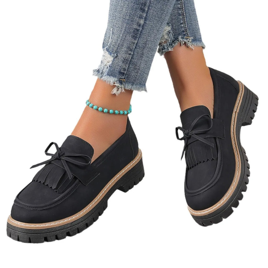 Black plus size women's loafers with a tassel and bowknot on a chunky rubber sole.