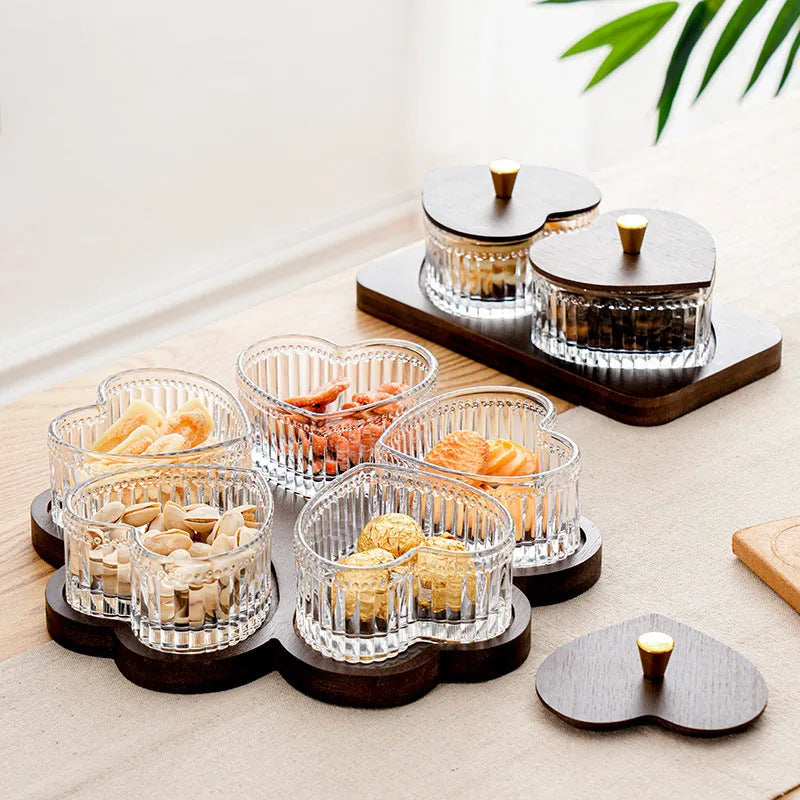 Glass foot bath fruit platter with coloured glaze and transparent heart-shaped lids on a multi-grid snack tray.