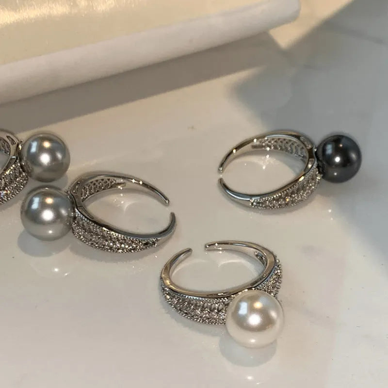 Geometric open copper ring with black pearl detail on a woman's index finger, showing adjustable opening.