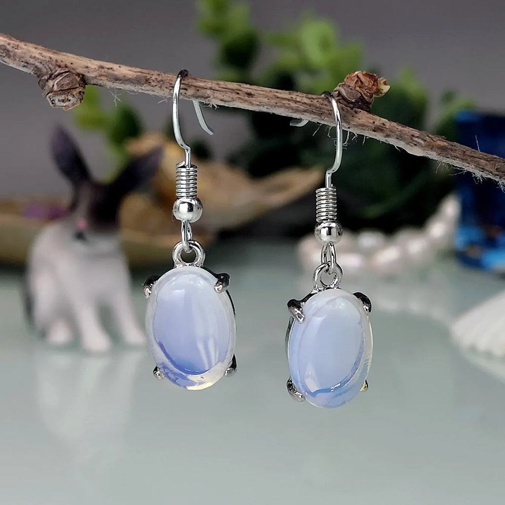 Pair of retro moonstone opal drop earrings with a cross design in moonlight white.