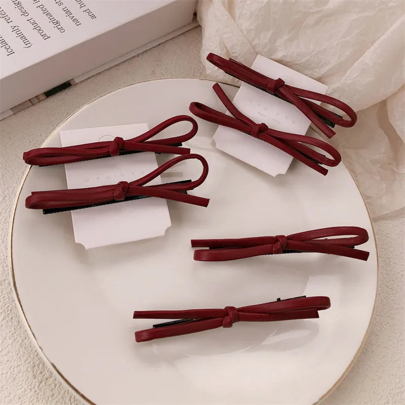 Wine red leather bow hair barrettes for women, showing front and side views