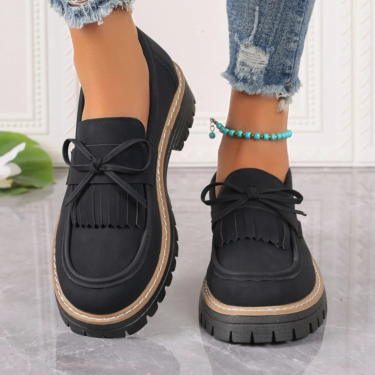 Black plus size women's loafers with a tassel and bowknot on a chunky rubber sole.