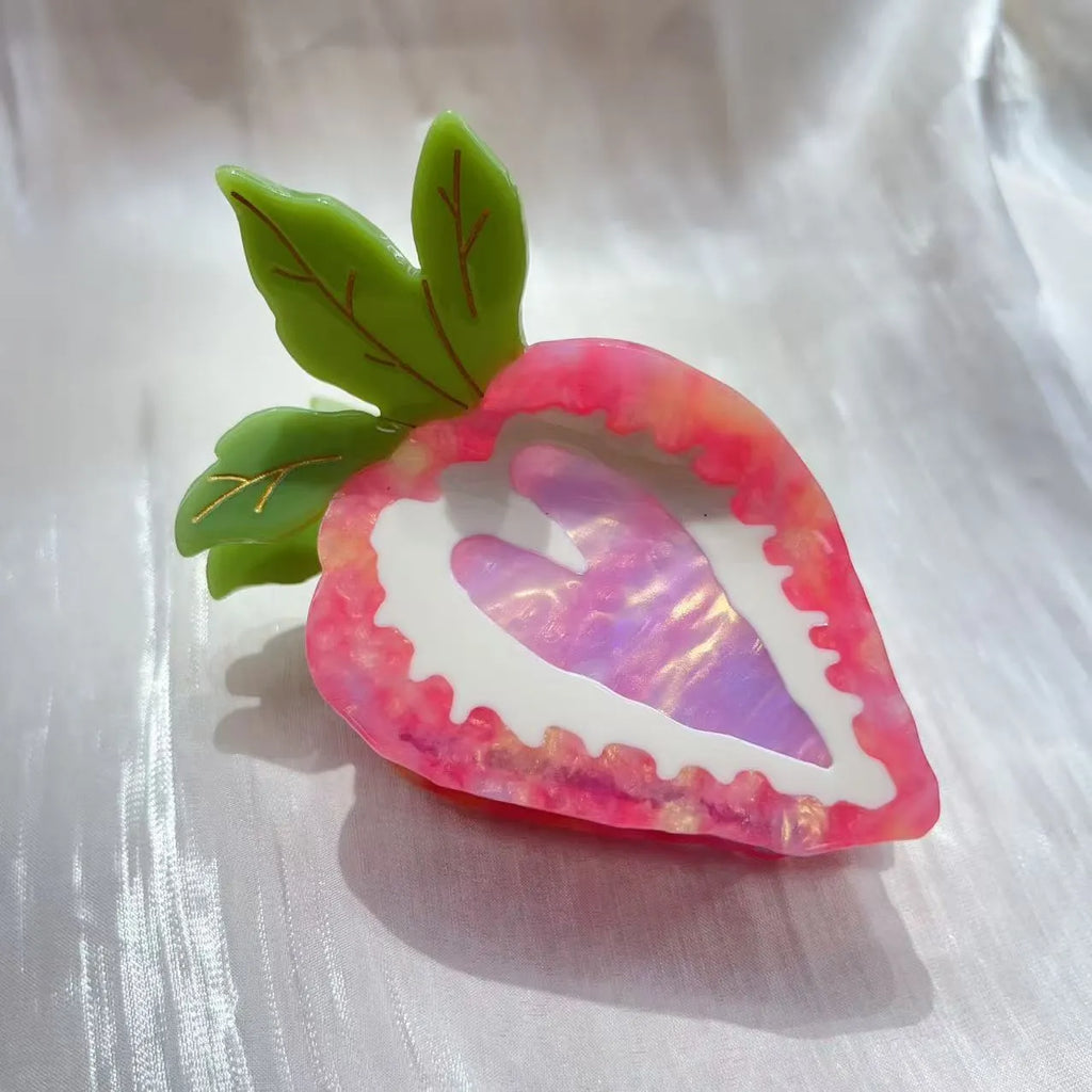 Close-up of a handmade strawberry hair clip in red or pink on a white background.