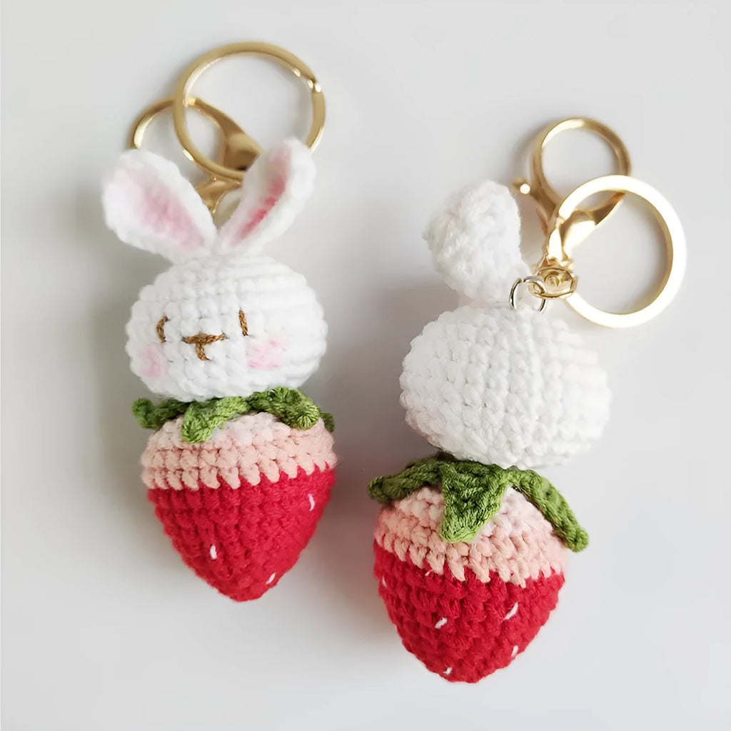 White hand-woven wire pendant in shape of a rabbit with a strawberry pattern, includes a key.