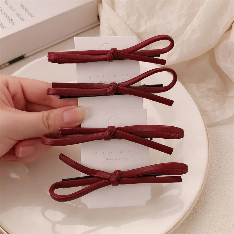 Wine red leather bow hair barrettes for women, showing front and side views