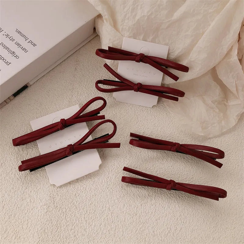 Wine red leather bow hair barrettes for women, showing front and side views
