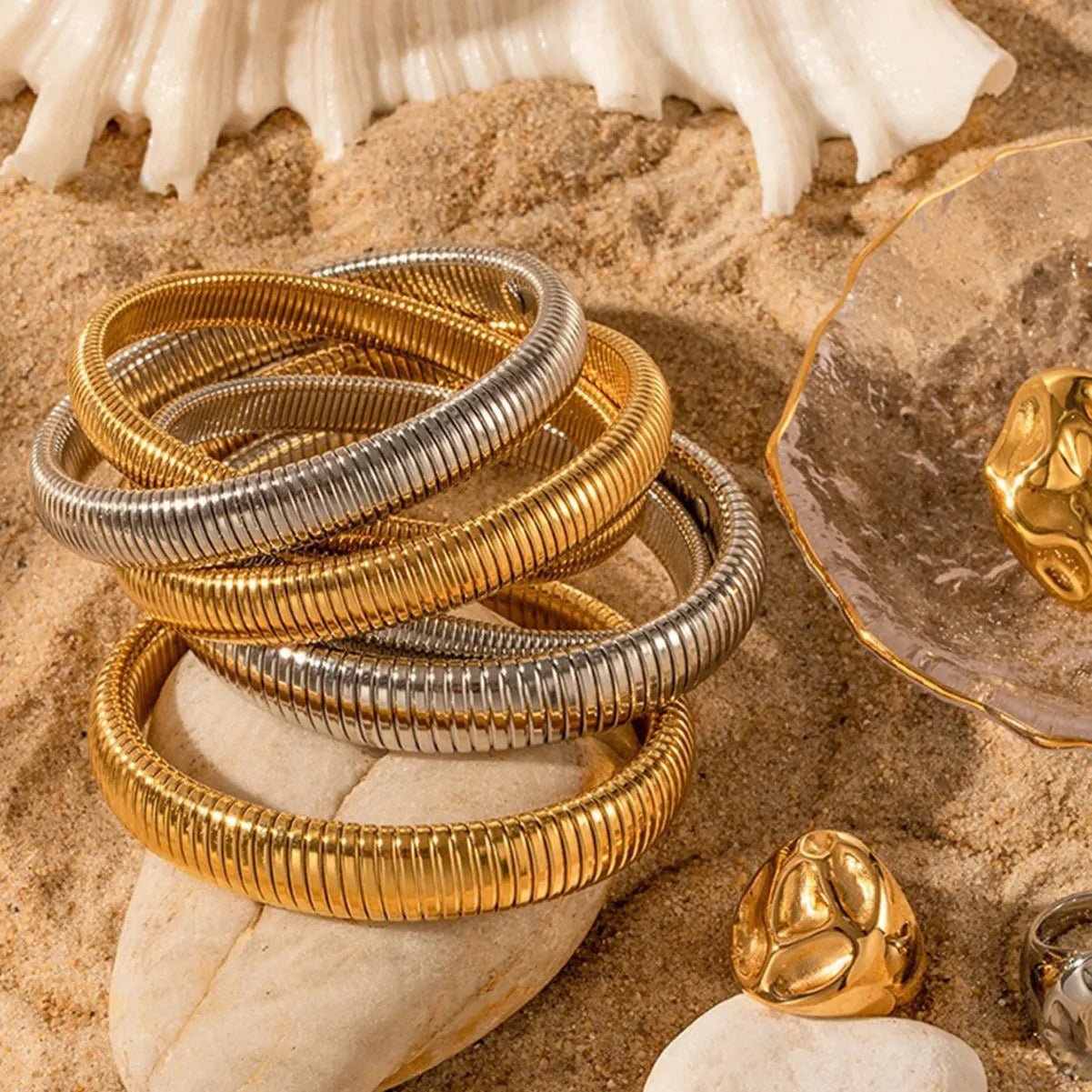 Gold titanium steel women's bracelet with elastic band and exaggerated vertical stripe ring pattern.