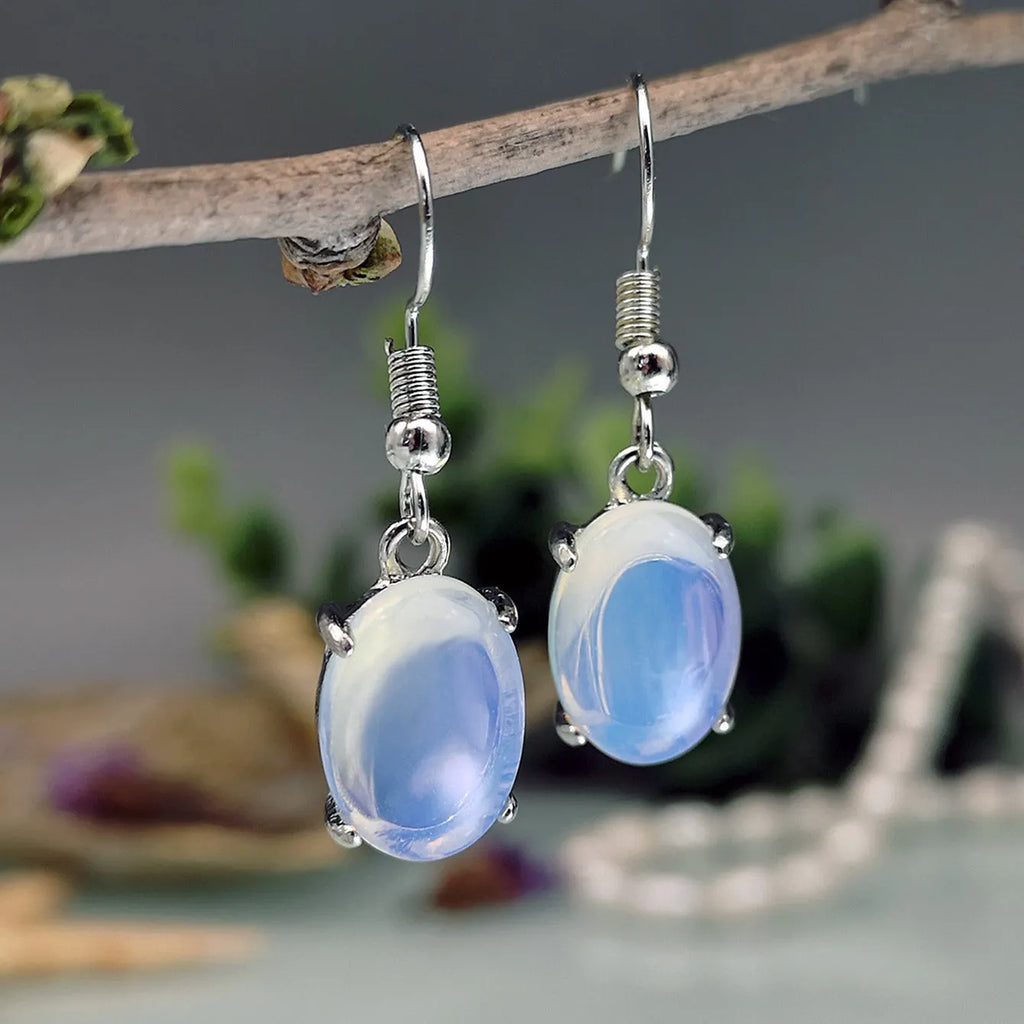 Pair of retro moonstone opal drop earrings with a cross design in moonlight white.