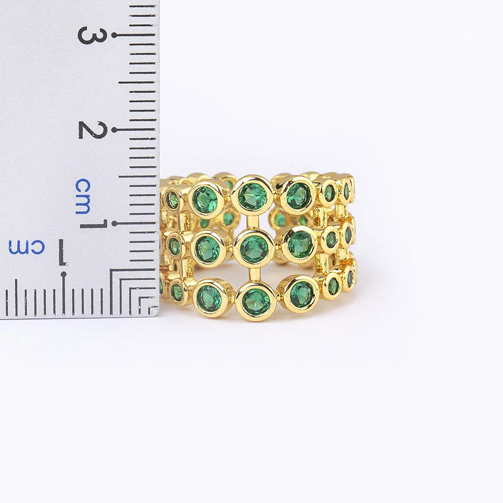 Gold coloured wide band ring with three layers of green zircons on a copper base plated with 18K real gold.