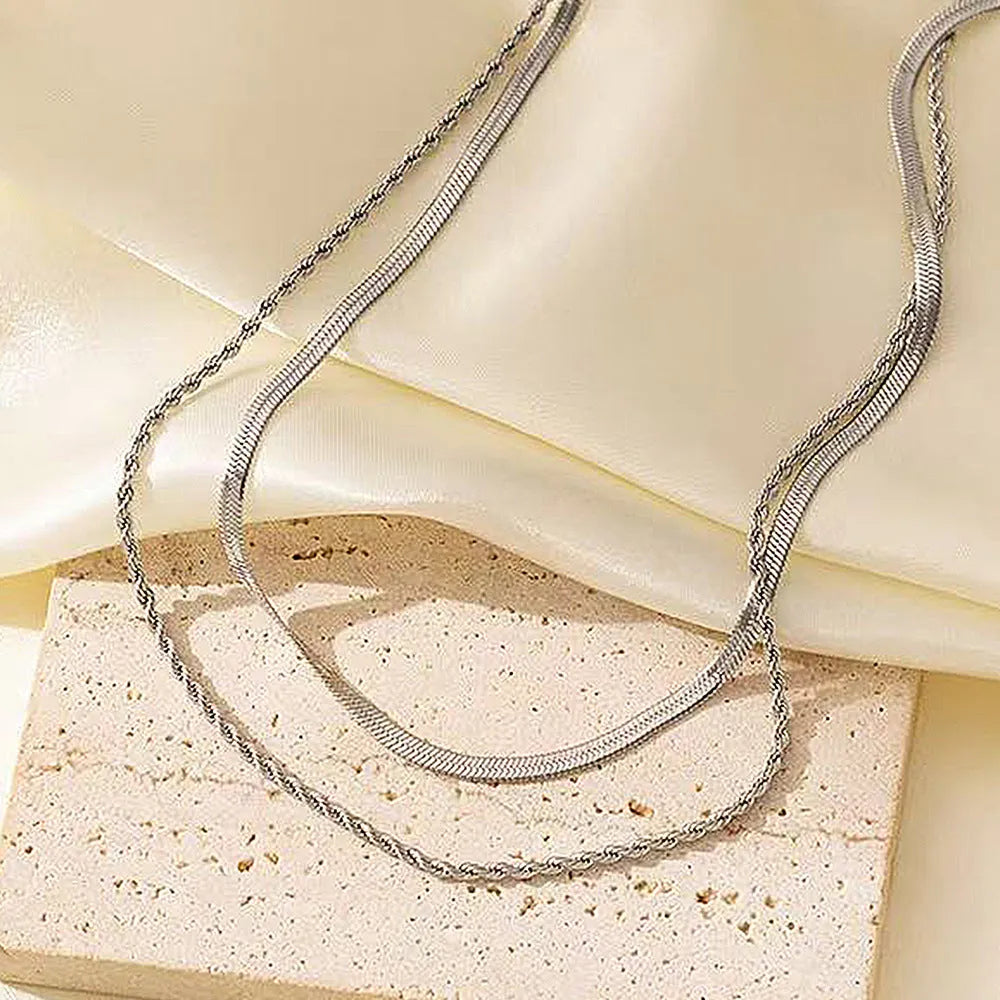 Geometric pendant necklace with snake bones chain in stainless steel, shown in a solid colour.