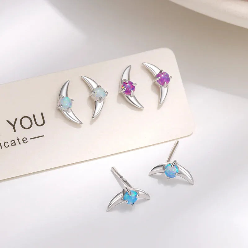 Close-up of women's geometric earrings in 925 silver with electroplated finish and a blue crystal stone.