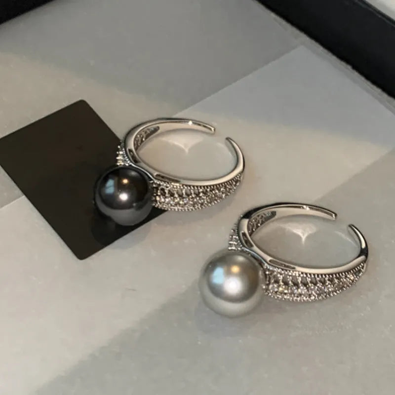 Geometric open copper ring with black pearl detail on a woman's index finger, showing adjustable opening.