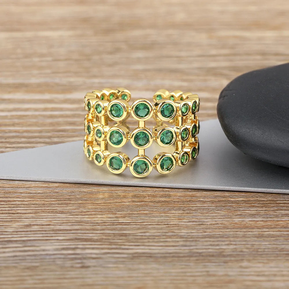 Gold coloured wide band ring with three layers of green zircons on a copper base plated with 18K real gold.