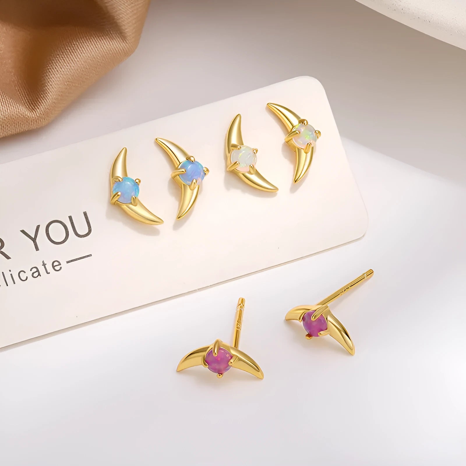 Close-up of women's geometric earrings in 925 silver with electroplated finish and a blue crystal stone.