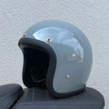Glass fibre motorcycle half helmet in retro style shown in cement grey colour