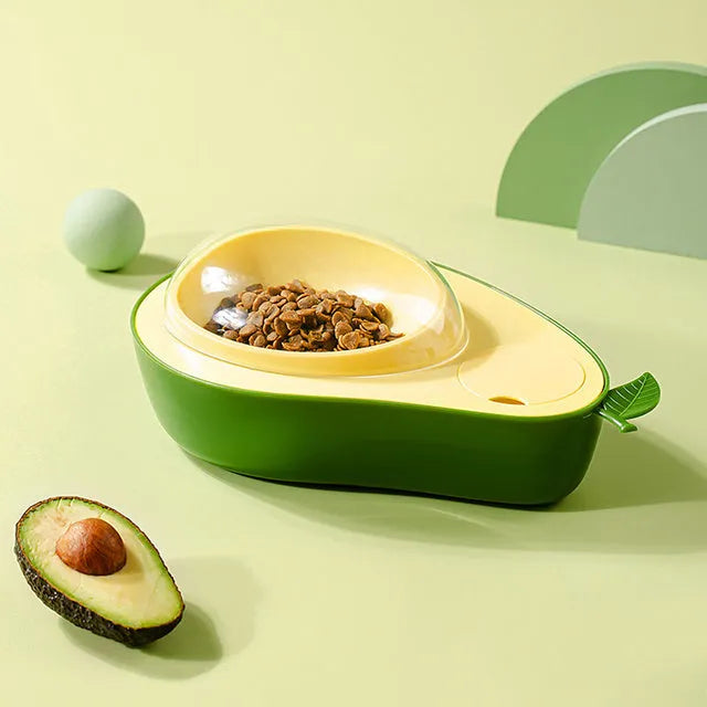 Avocado-shaped automatic water pet feeder with a green water reservoir and a pink slow food bowl on a white surface