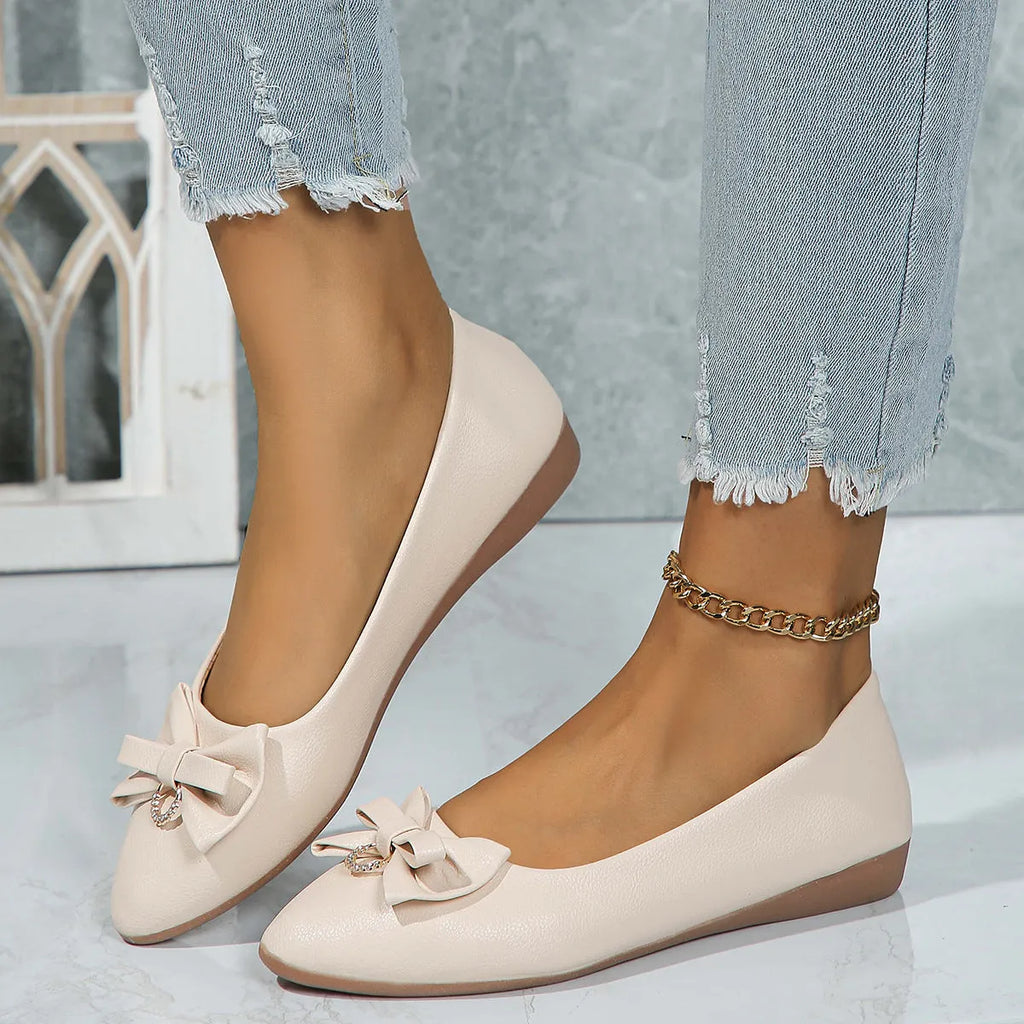 Women's beige casual flat loafers with a bowknot on the front, showing the shallow mouth and rubber sole.