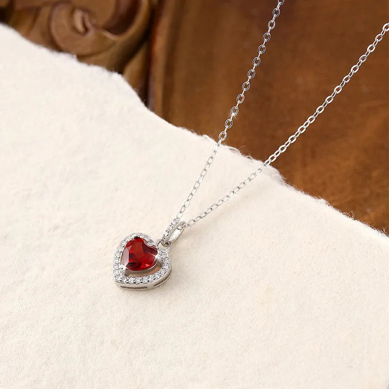 Women's sterling silver heart pendant necklace with a coloured gemstone on an adjustable chain.