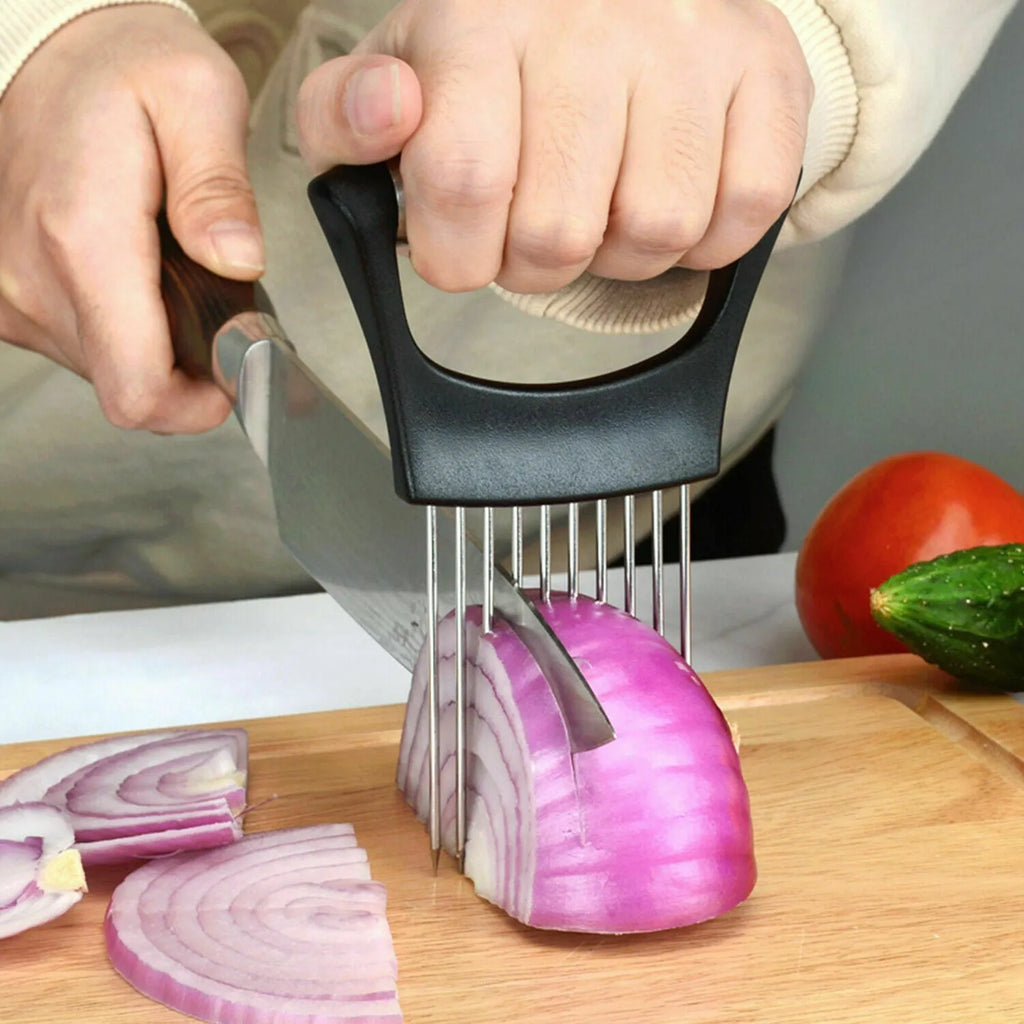 Stainless steel onion holder slicer with non-slip base on a kitchen counter next to a tomato and knife