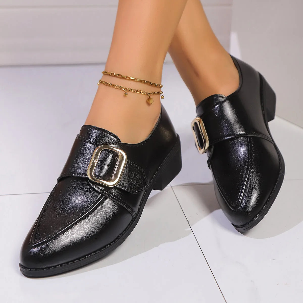 Women's leather-look slip-on shoes with decorative bow buckle detail and pointed toe