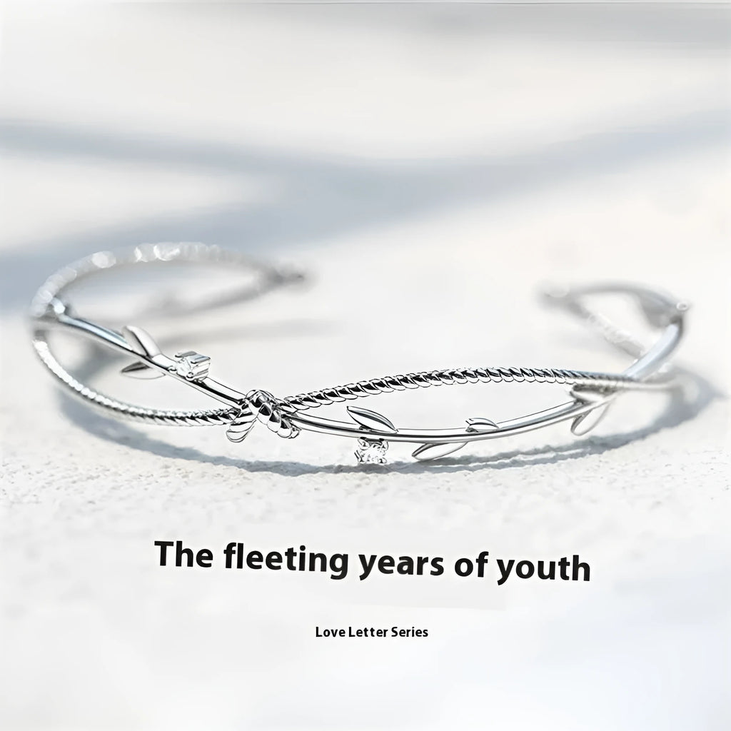 Cross twisted branch sprout bracelet in electroplated white gold Z4136 on a natural background