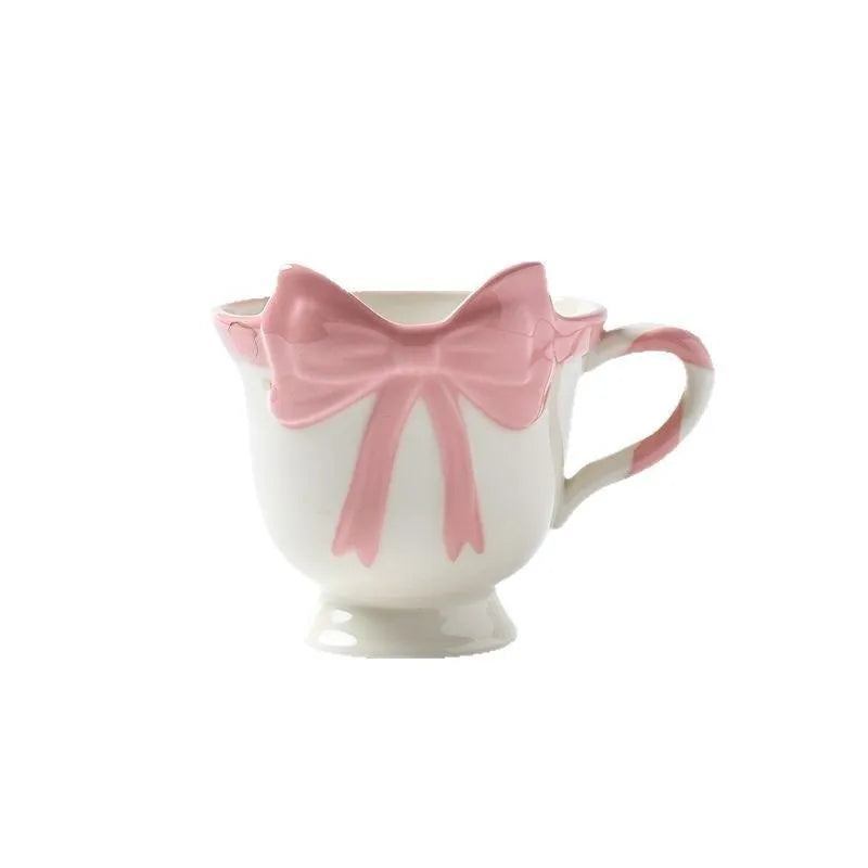 White ceramic mug with a pink heart and black bow design, 350ml capacity.