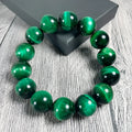 Green polished Tiger Eye stone bracelet with geometry beads, shown on a wrist.