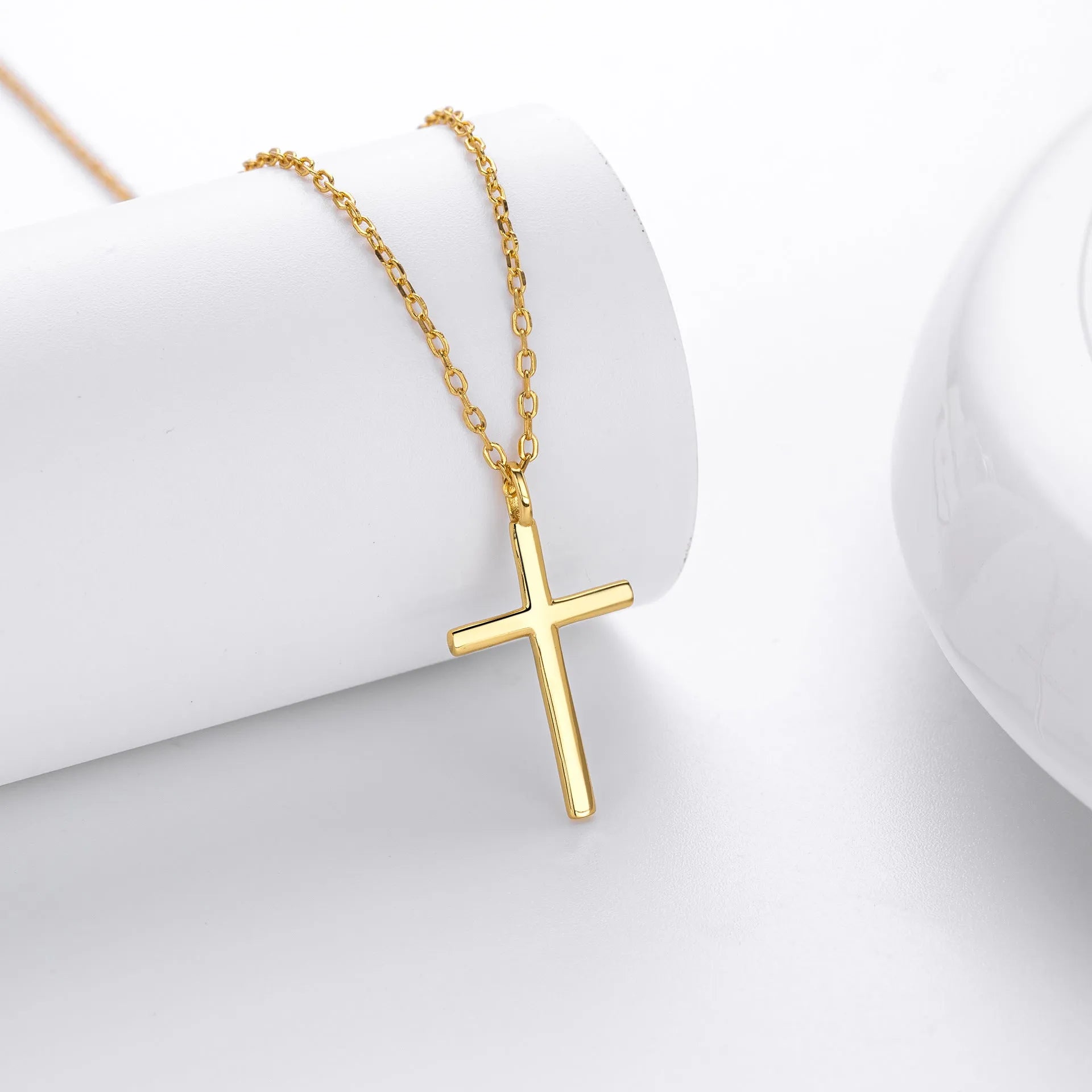 Simple glossy cross pendant on an O-chain sterling silver necklace in gold plating.