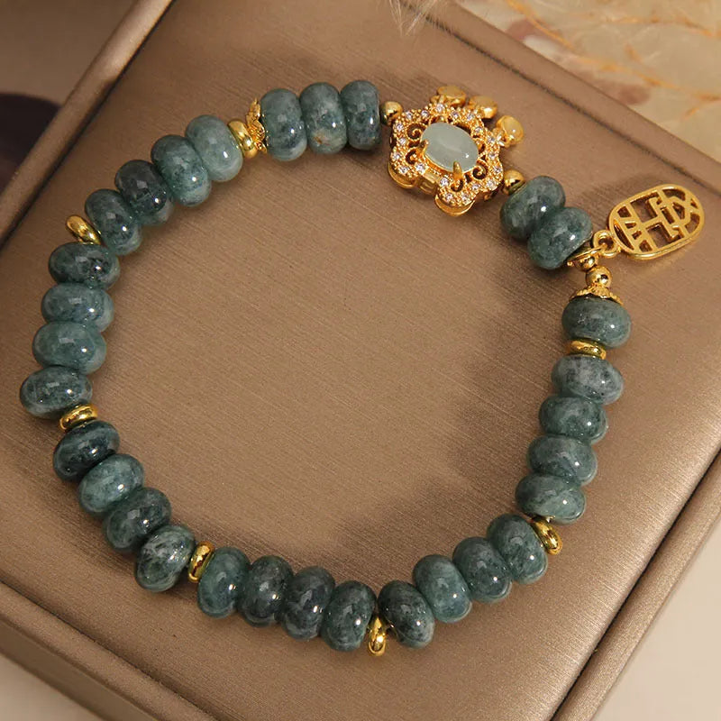 Close-up of a women's bracelet with green emerald jade abacus beads and a metallic alloy safety lock clasp.