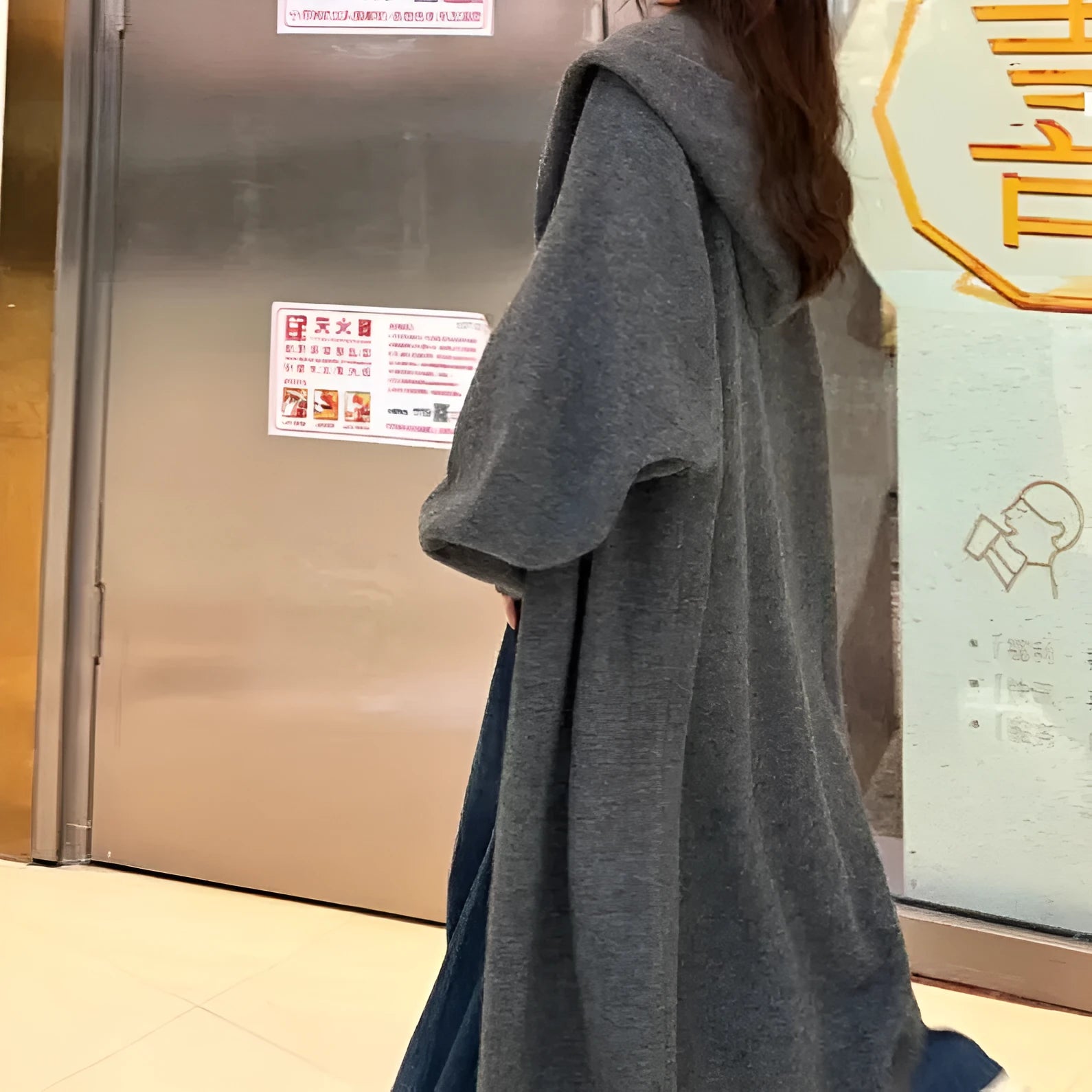 Woman wearing a long, loose, hooded knitted cardigan in a neutral colour, Korean casual style.