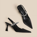 Women's black stiletto heel sandals with pointed closed toe, buckle strap, and skirt detail on a white background