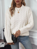 Woman wearing a loose beige round neck sweater with a twisted knit texture detail on the front.