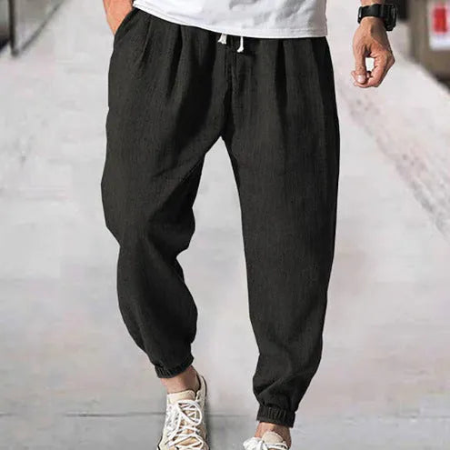 Men's loose cotton ankle banded trousers in khaki colour on a hanger.