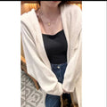 Woman wearing a long, loose, hooded knitted cardigan in a neutral colour, Korean casual style.
