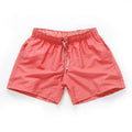 Men's straight-leg beach shorts in black polyester fabric on a size chart.