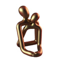 Modern couple resin statue in gold colour placed on a white bookshelf as home decor accent