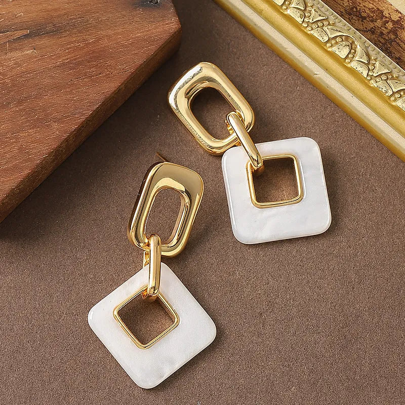 Dignified hollow geometric square copper earrings with electroplated finish on white background