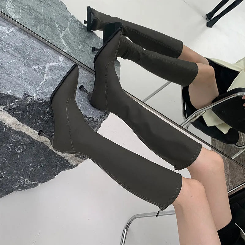 Black women's below-the-knee pointed toe stiletto boots with a back zipper on a white background