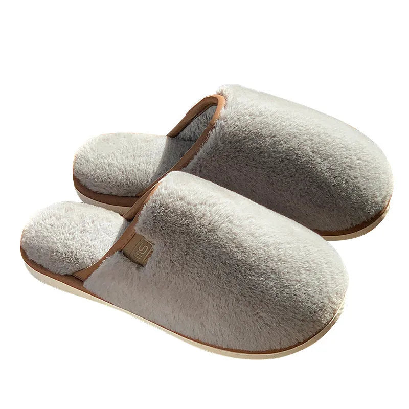 Solid colour winter plush slippers with non-slip PVC sole on a wooden floor.