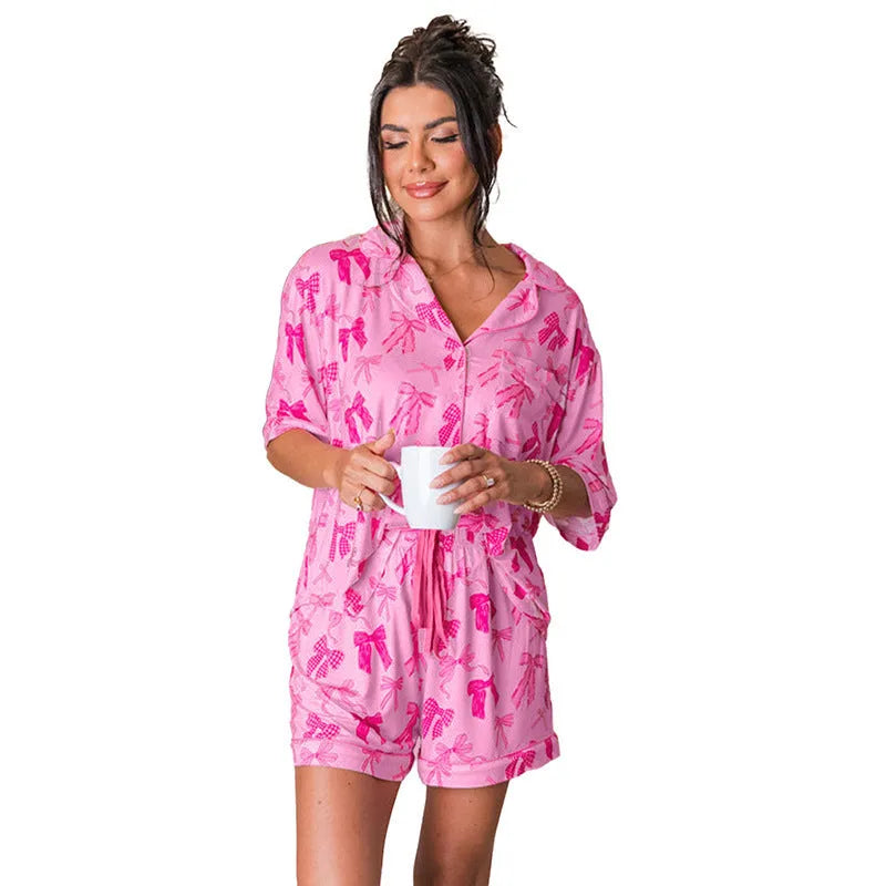 Pink women's two-piece pyjama set with a bow print detail on the top.