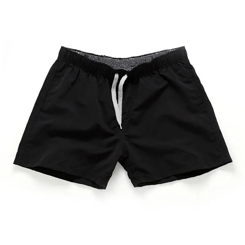Men's straight-leg beach shorts in black polyester fabric on a size chart.