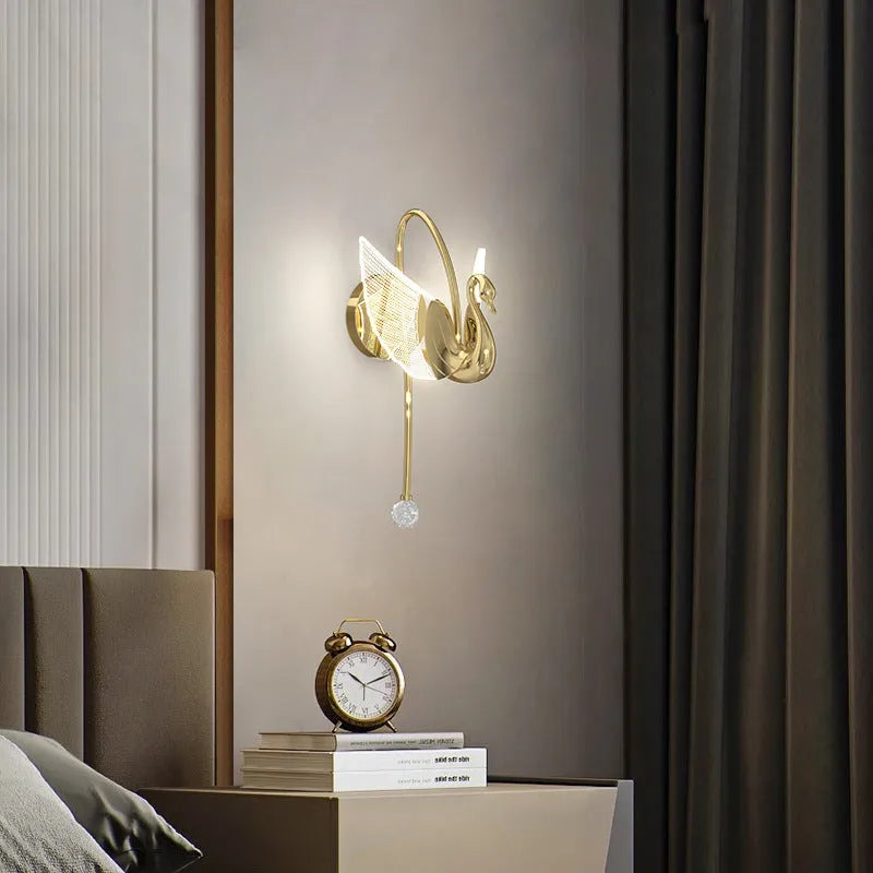 Modern gold swan-shaped wall lamp with acrylic shade mounted beside bed