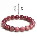 Natural red strawberry quartz crystal bracelet with geometric beads showing a starlight effect, laid flat.