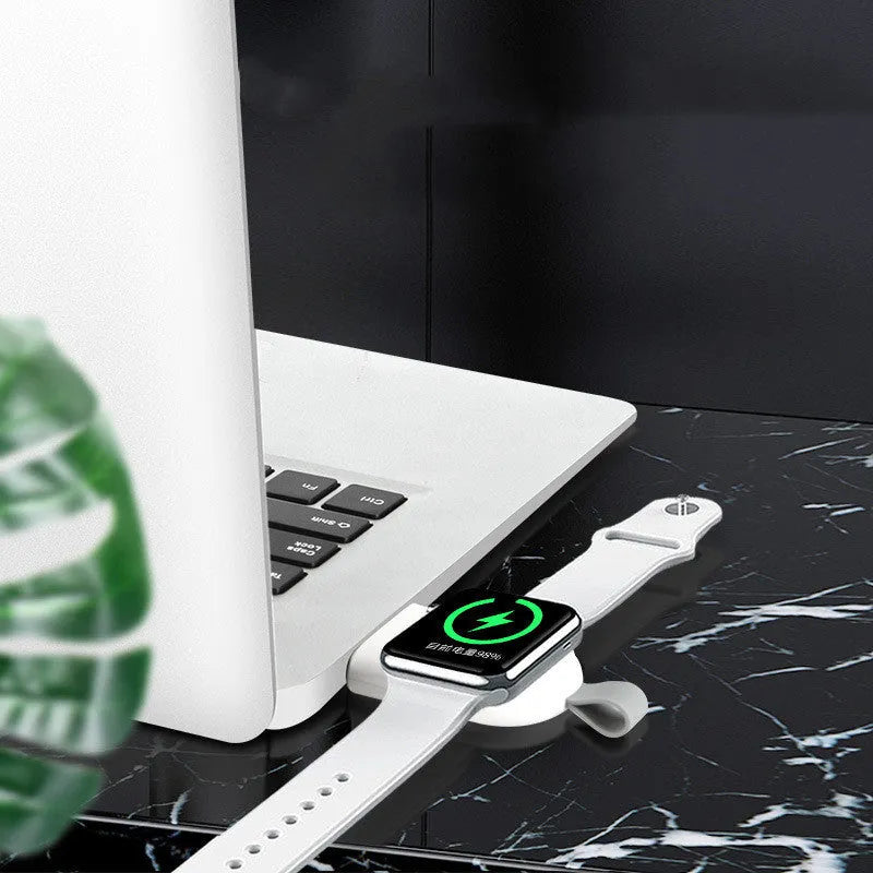 Portable wireless Apple Watch charging dock in white on a desk, with USB cable attached