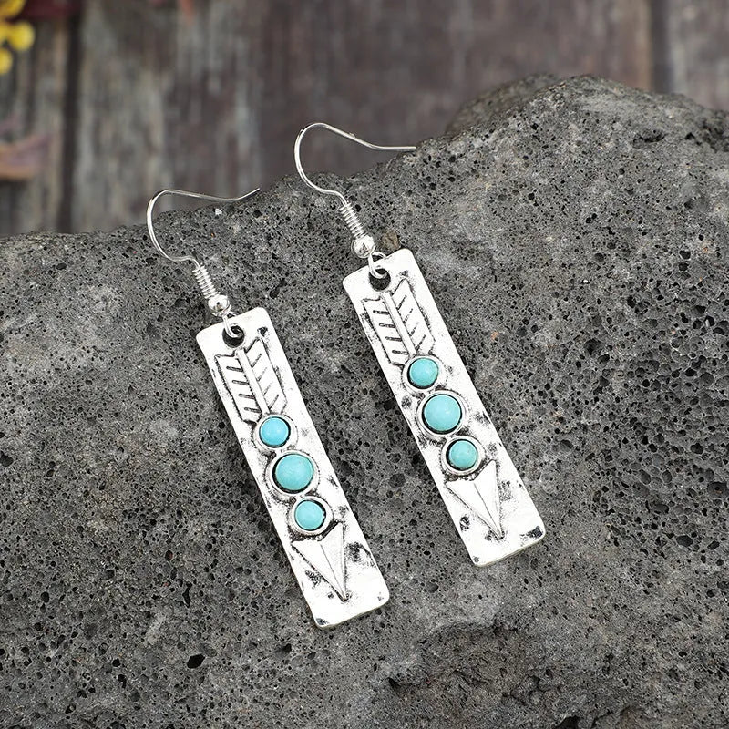 Long strip geometric silver earrings with inlaid turquoise detail on a white background