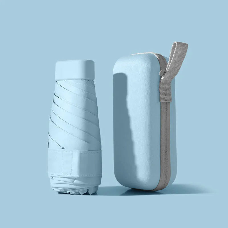 Compact six-fold umbrella in mint green with a capsule box, showing its folded size and rubber handle.