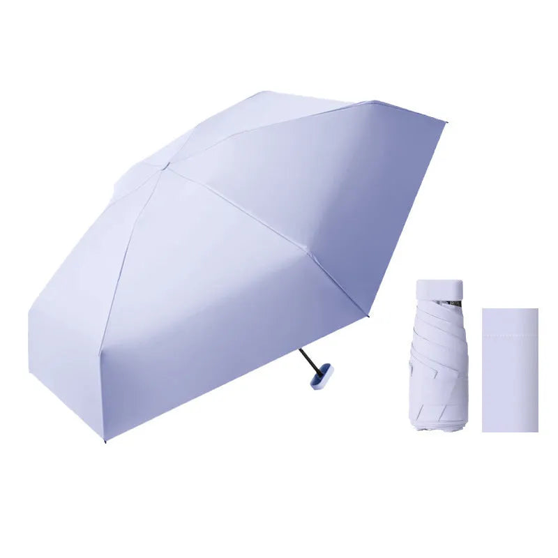 Compact six-fold umbrella in mint green with a capsule box, showing its folded size and rubber handle.