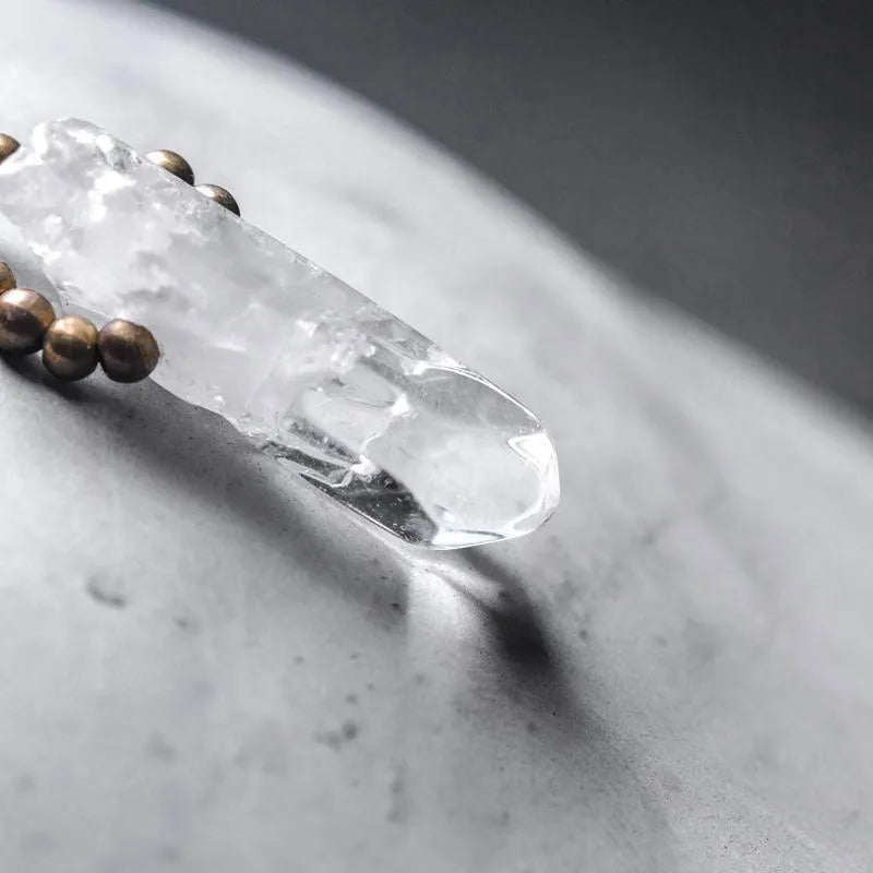 Black hair crystal bracelet with white crystal tassel and bending and lacing design on neutral background
