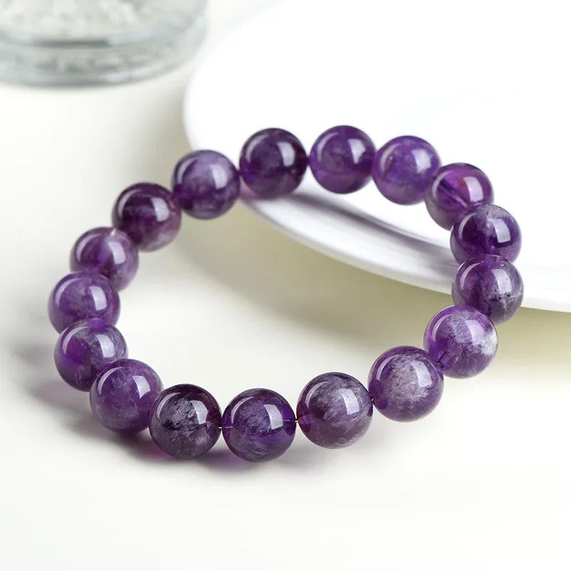 Natural purple feather amethyst crystal bracelet with scattered beads and geometric Ruyi pattern on a wrist.